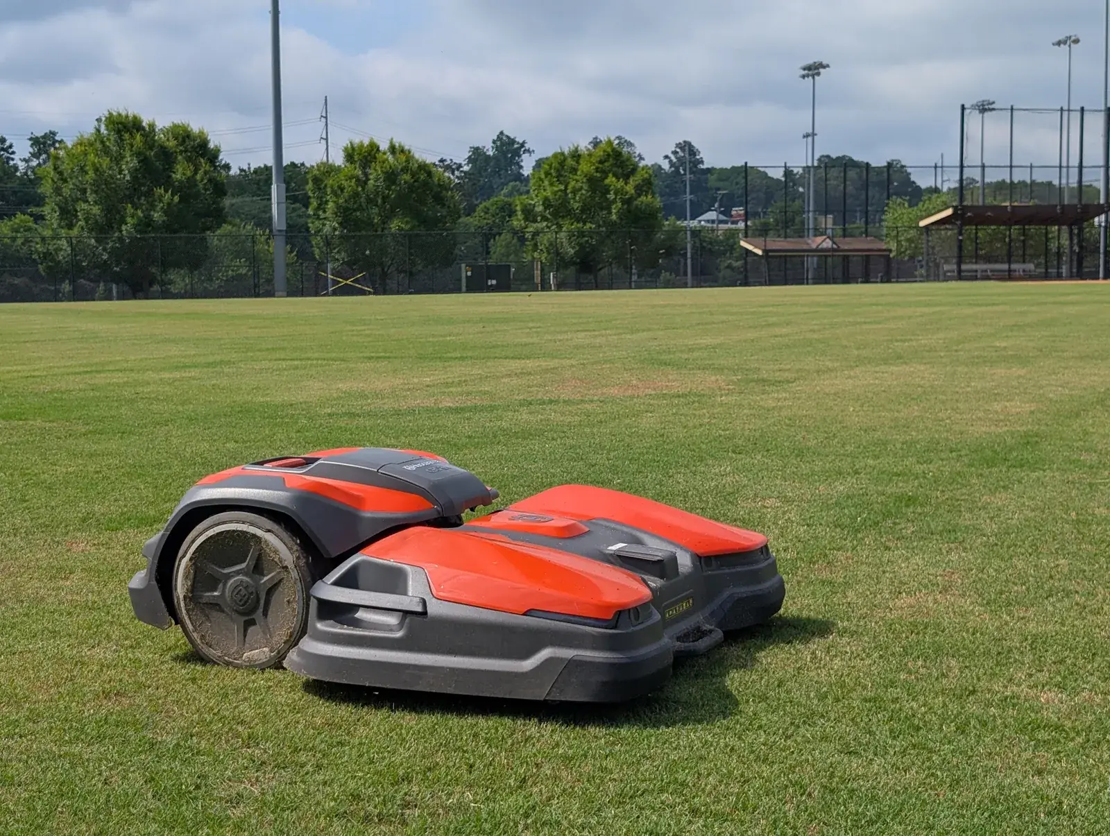 Two Husqvarna CEORA robotic mowers side by side on an athletic field